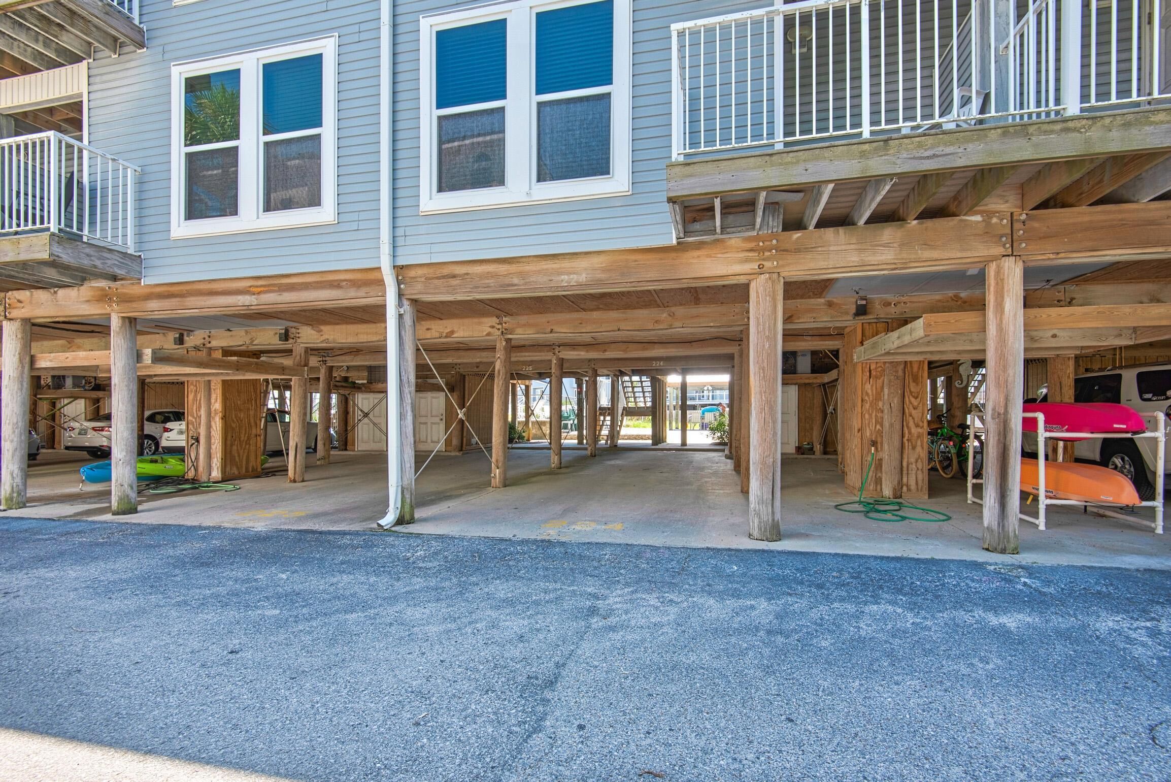 A two-story building with a covered parking area and a balcony.