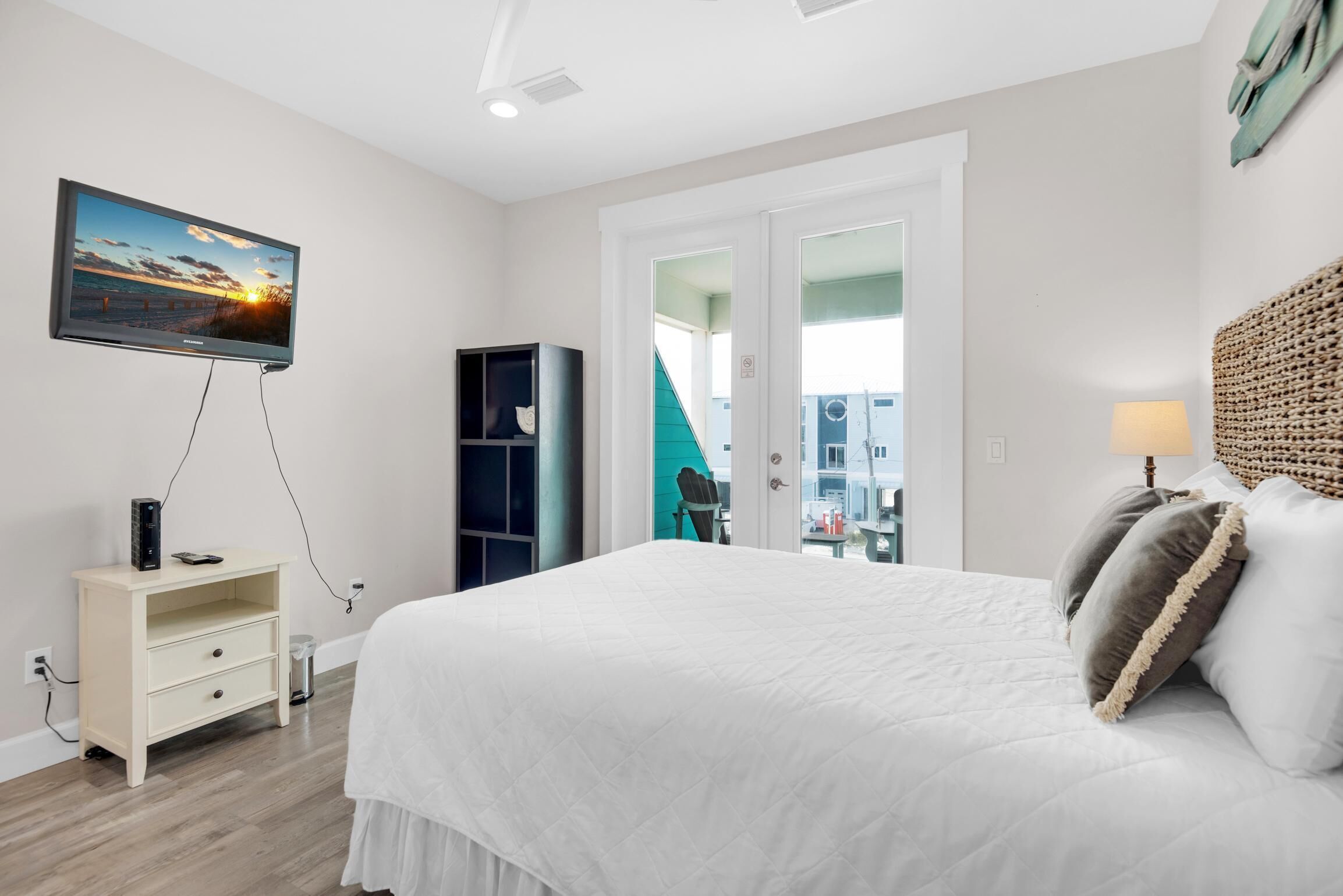 Quarto com cama, televisão, estante de livros e vista para um prédio.