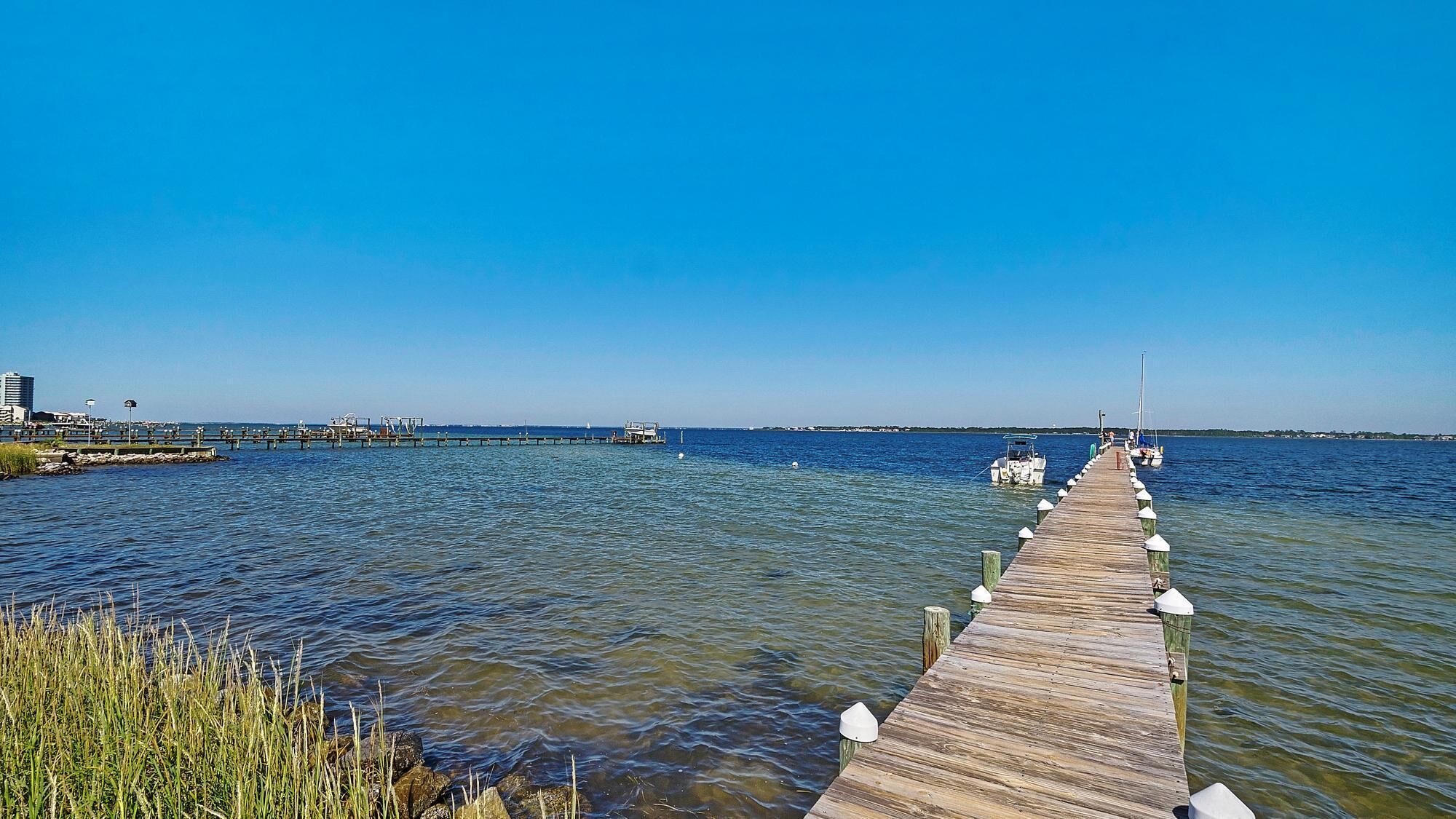 A wooden pier extending into calm waters, with a clear sky above.
