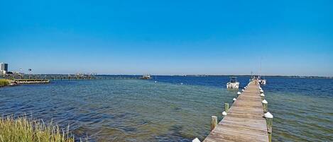 A wooden pier extending into calm waters, with a clear sky above.