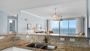 Une cuisine dotée de plans de travail en granit, d’un évier double et offrant une vue sur l’océan grâce à une grande fenêtre.