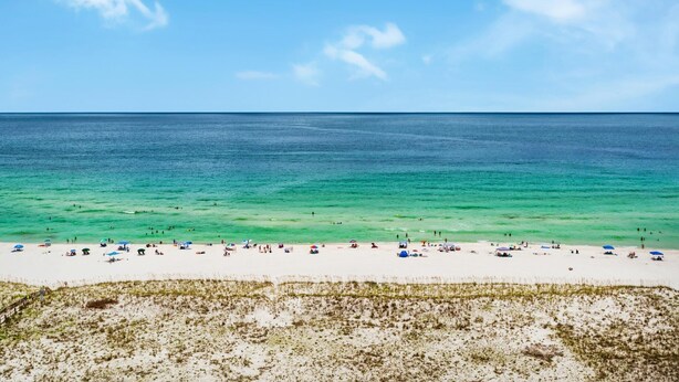 Une plage à l’eau turquoise et limpide, bordée d’un rivage sablonneux.