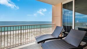 Un balcon avec deux fauteuils de jardin donnant sur une plage.