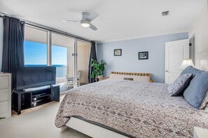 A bedroom with a bed, a TV, a ceiling fan, and a balcony with a view. - Starboard Village 622 (Pensacola Beach)