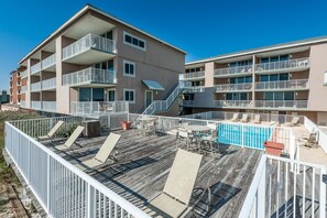 A multi-story hotel with a rooftop pool area, outdoor seating, and a wooden deck. - Starboard Village 622 (Pensacola Beach)