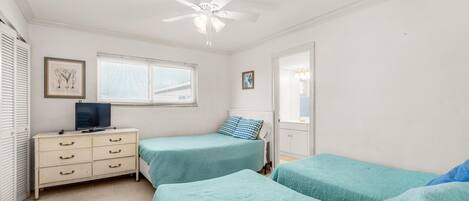 A bedroom with two beds, a dresser, a ceiling fan, and a window with blinds.