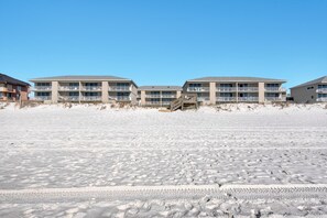 A beachfront hotel with multiple floors, balconies, and a wooden walkway leading to the beach. - Starboard Village 622 (Pensacola Beach)