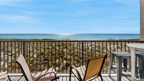 A balcony with two chairs and a table, overlooking a beach with dunes and the ocean. - Sundunes 112 (Navarre)
