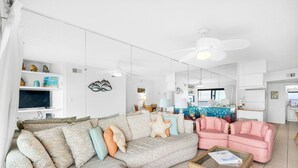 A modern living room with a sectional sofa, a pink armchair, and a glass coffee table. - Sundunes 112 (Navarre)