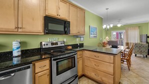 A kitchen with wooden cabinets, a microwave, a stove, and a dining area with chairs and a table.
