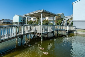 A wooden pier with a covered seating area, extending over a body of water. - Villas on the Gulf Unit J1 (Pensacola Beach)