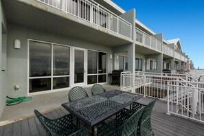 Eine Terrasse mit Tisch, Stühlen, einem Grill und einem Geländer.