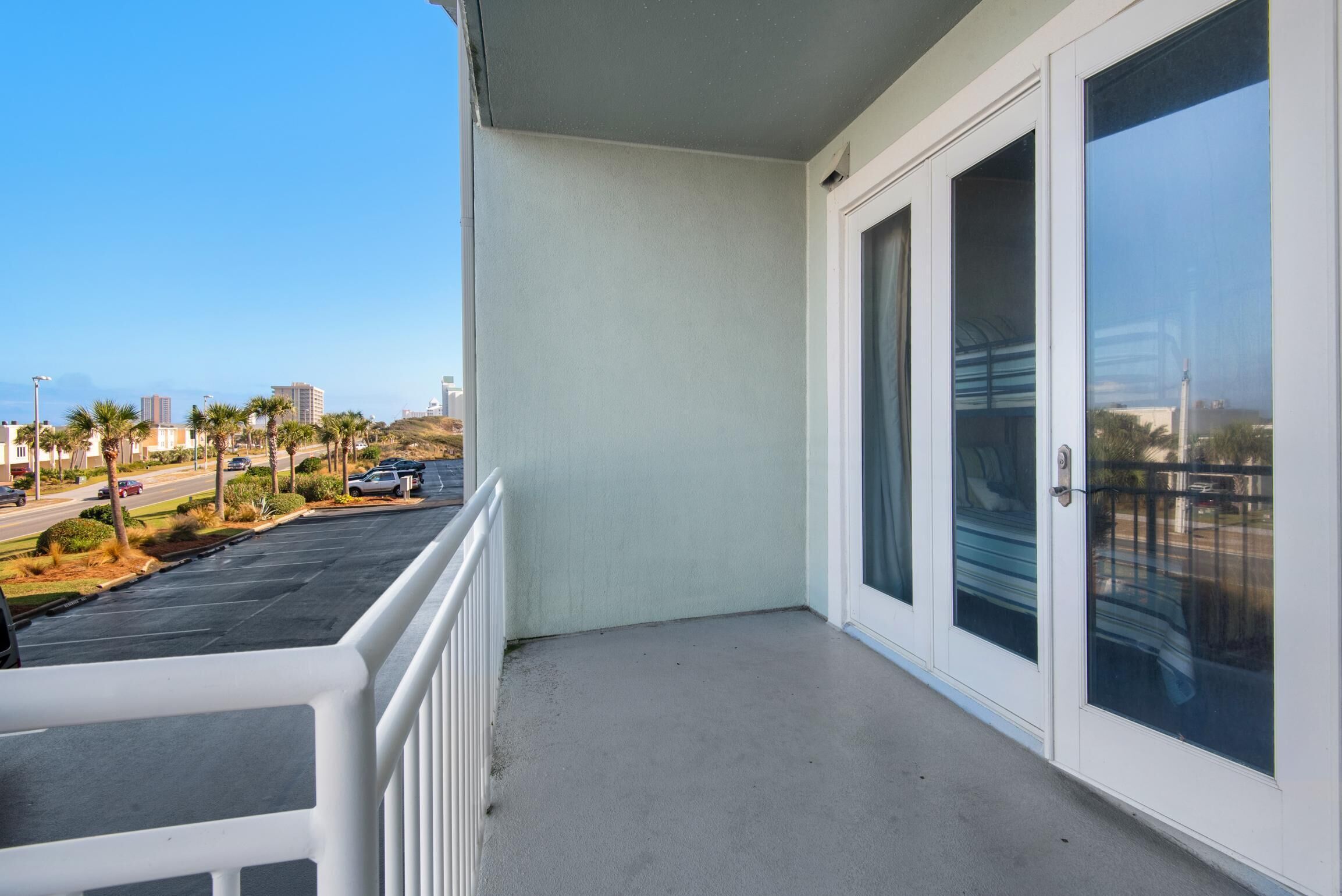 A balcony with a view of a parking lot and palm trees.