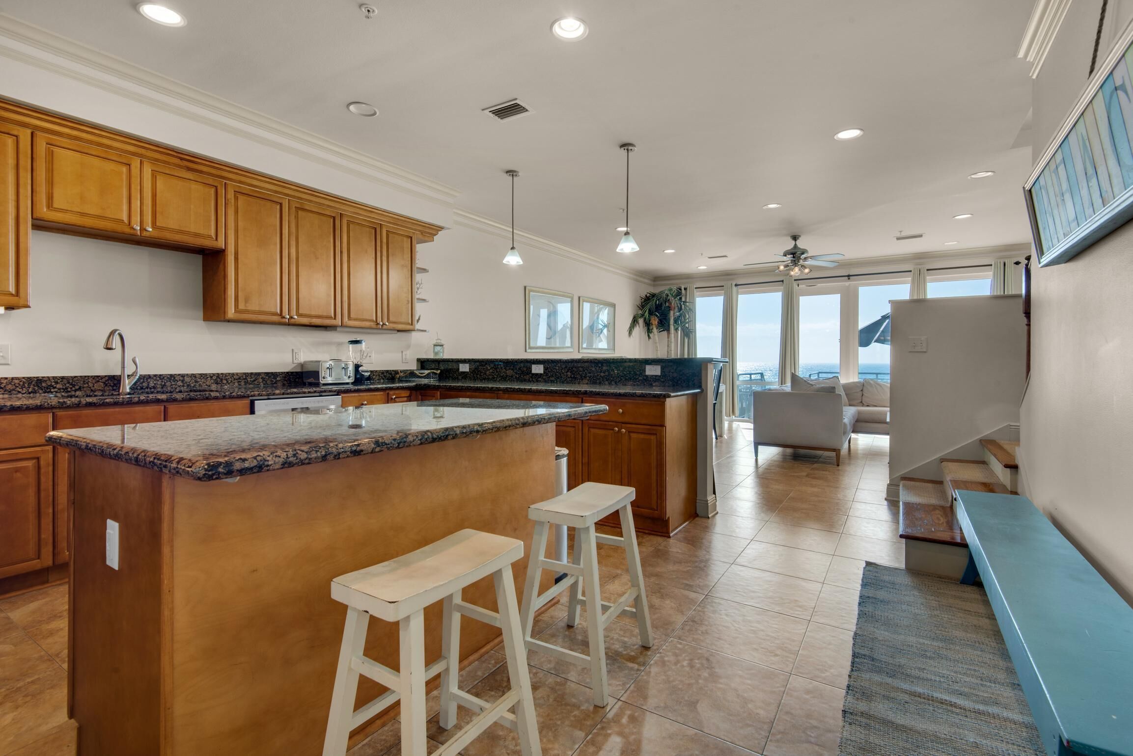 Una cocina moderna con armarios de madera, encimera de granito y una isla grande con taburetes de bar.
