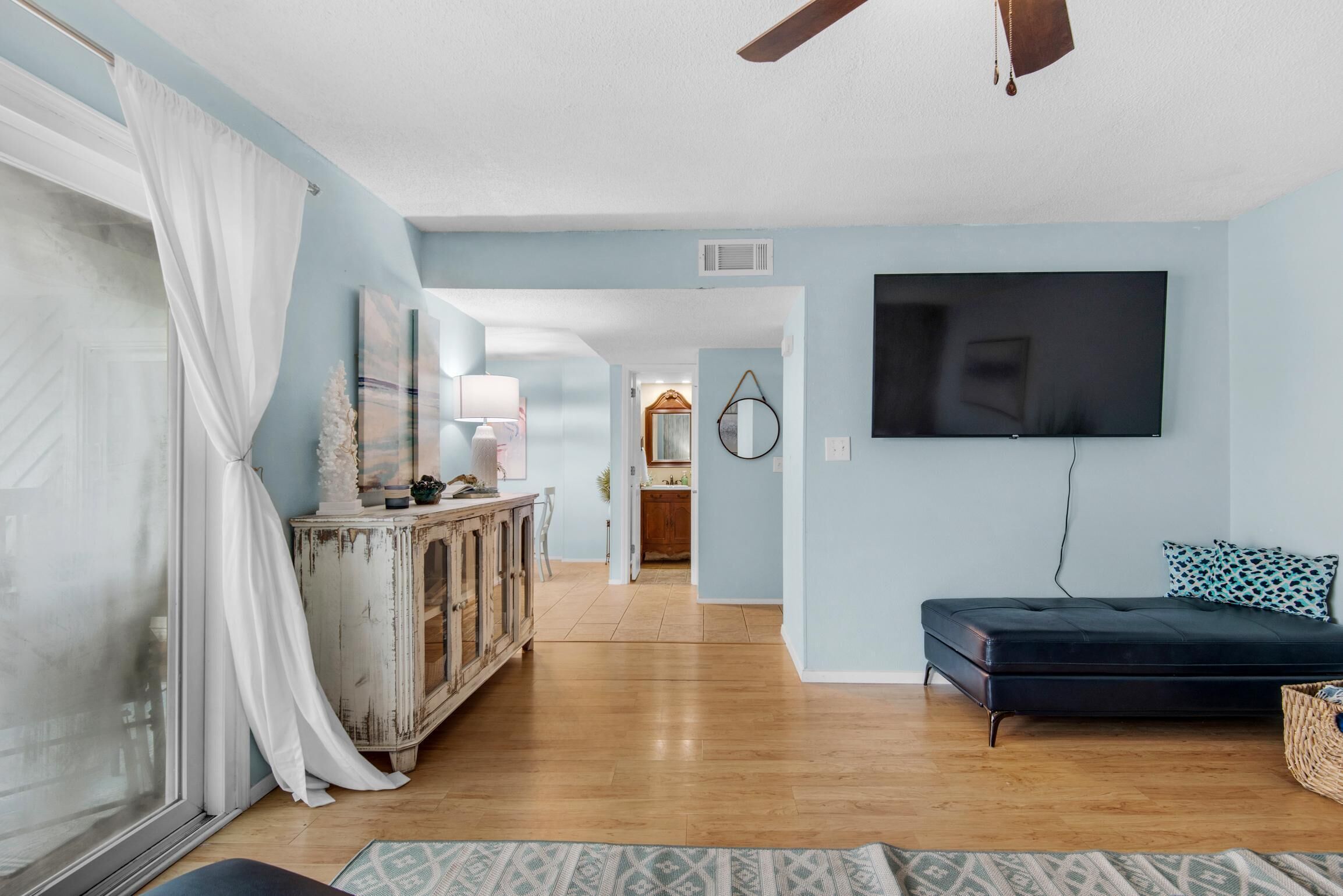 A living room with a TV, a sofa, a cabinet, and a window with curtains.