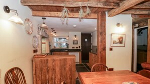 A rustic kitchen with wooden beams, a dining table, chairs, and a kitchen counter. - Eden Vale (Broughton in Furness)