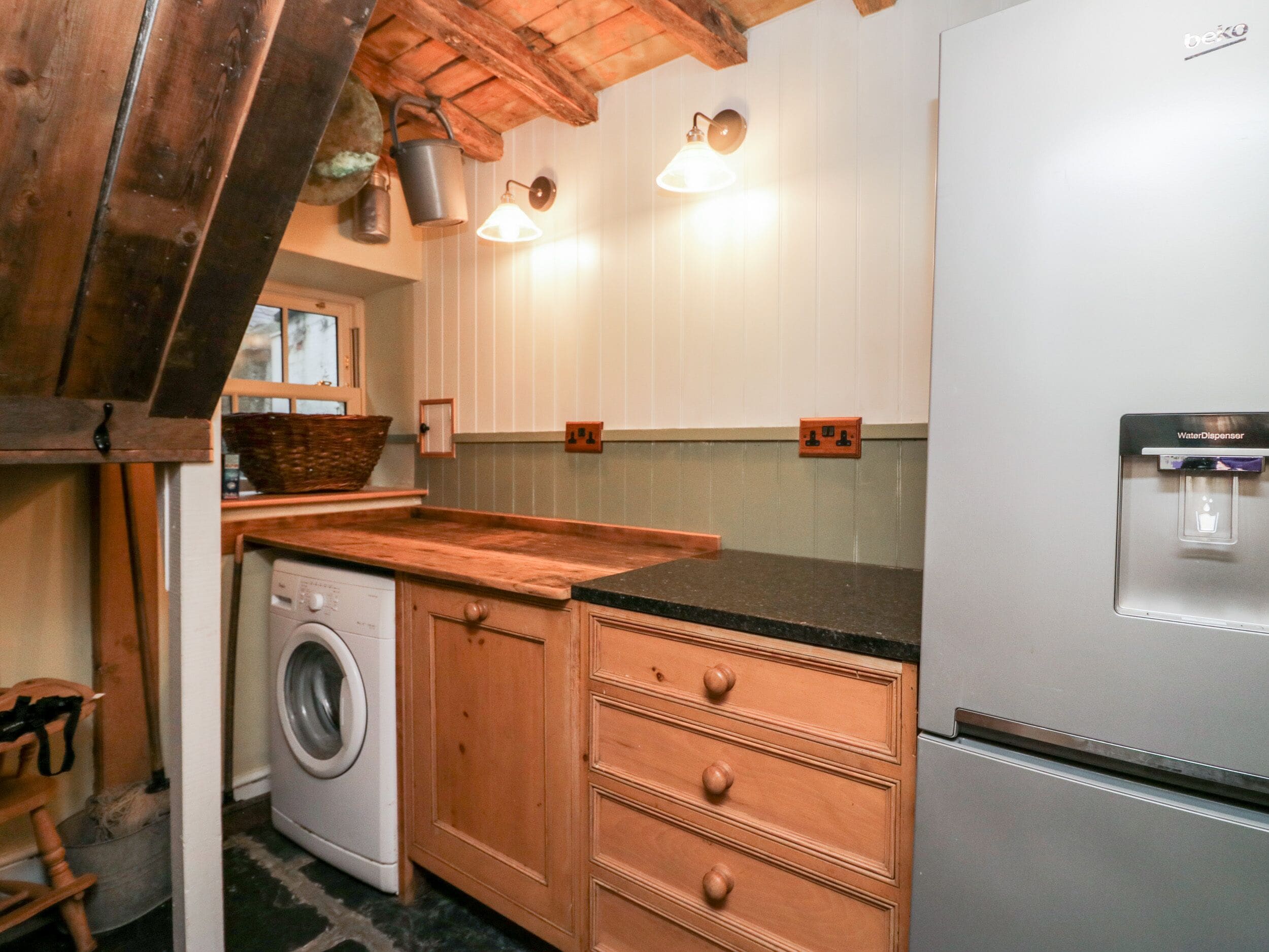 A compact kitchen with wooden cabinets, a washing machine, and a refrigerator.