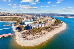 Vista aérea de una zona costera con edificios, un muelle y una playa.