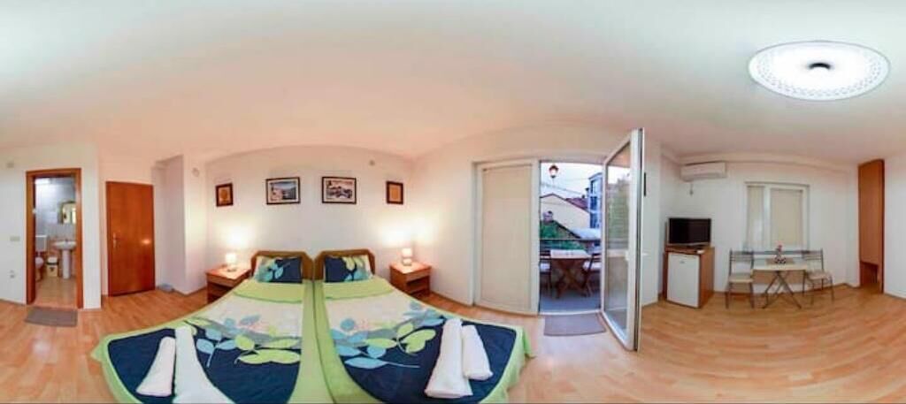 A spacious room with a large bed, a desk, and a balcony.
