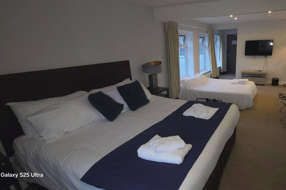 A hotel room with two beds, a flat-screen TV, a desk, and a chair.