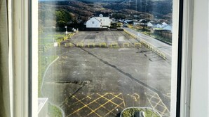A view from an airplane window of a parking lot with yellow barriers, a building with a white facade, and a clear blue sky. - The Springfield Fairbourne (Fairbourne)