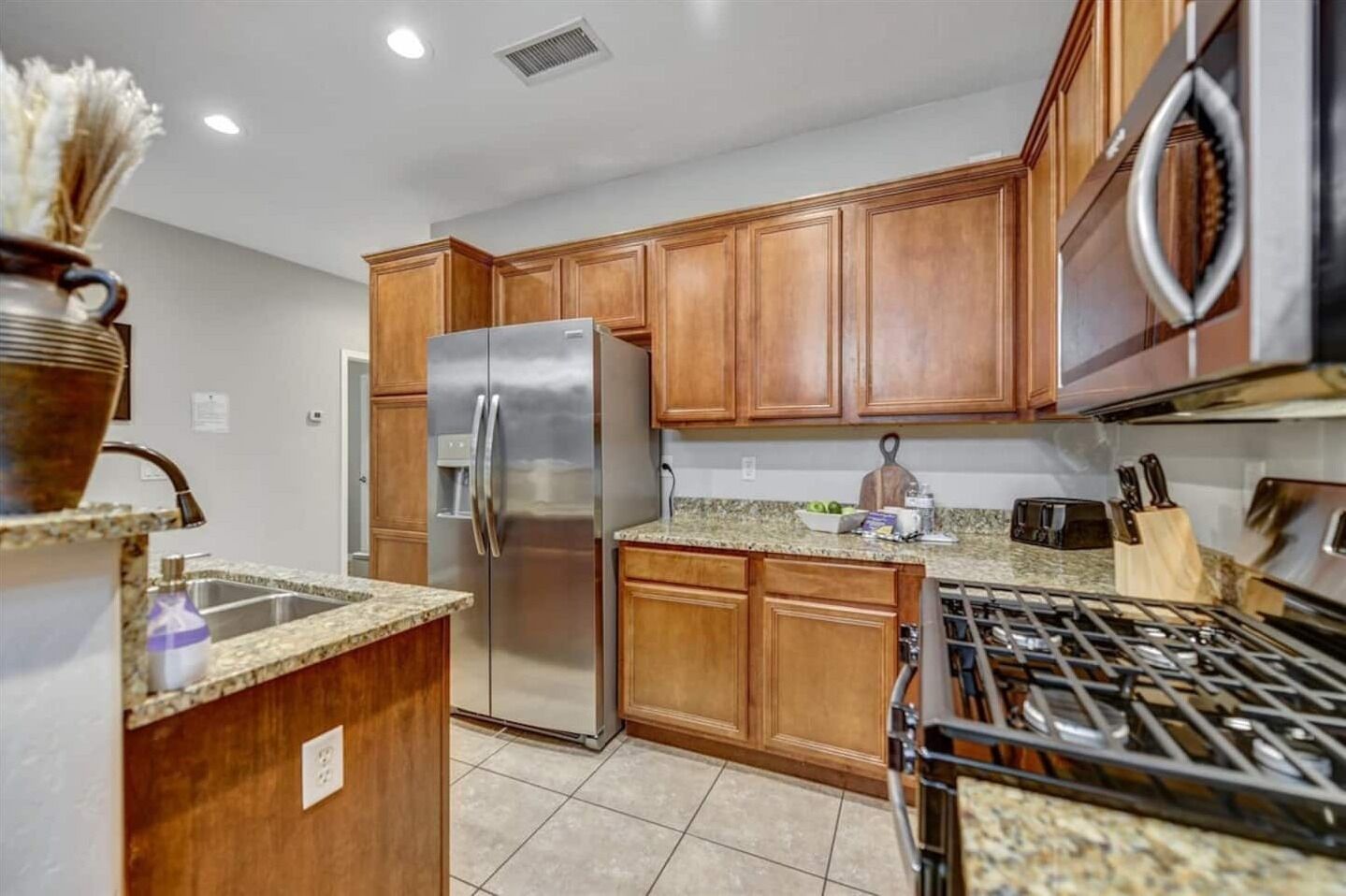 A modern kitchen with wooden cabinets, stainless steel appliances, and granite countertops.