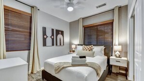 A modern hotel room with a large bed, bedside tables, and artwork on the walls.