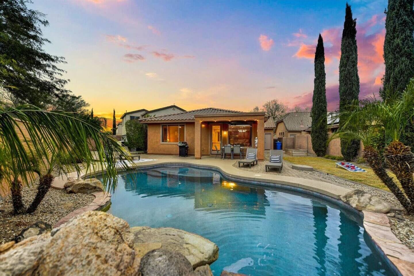 A residential property with a swimming pool, a covered patio, and a well-maintained garden.