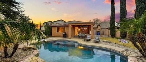 A residential property with a swimming pool, a covered patio, and a well-maintained garden.