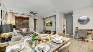 A modern living room with a dining area, featuring a sofa, a coffee table, and a dining table set for a meal.