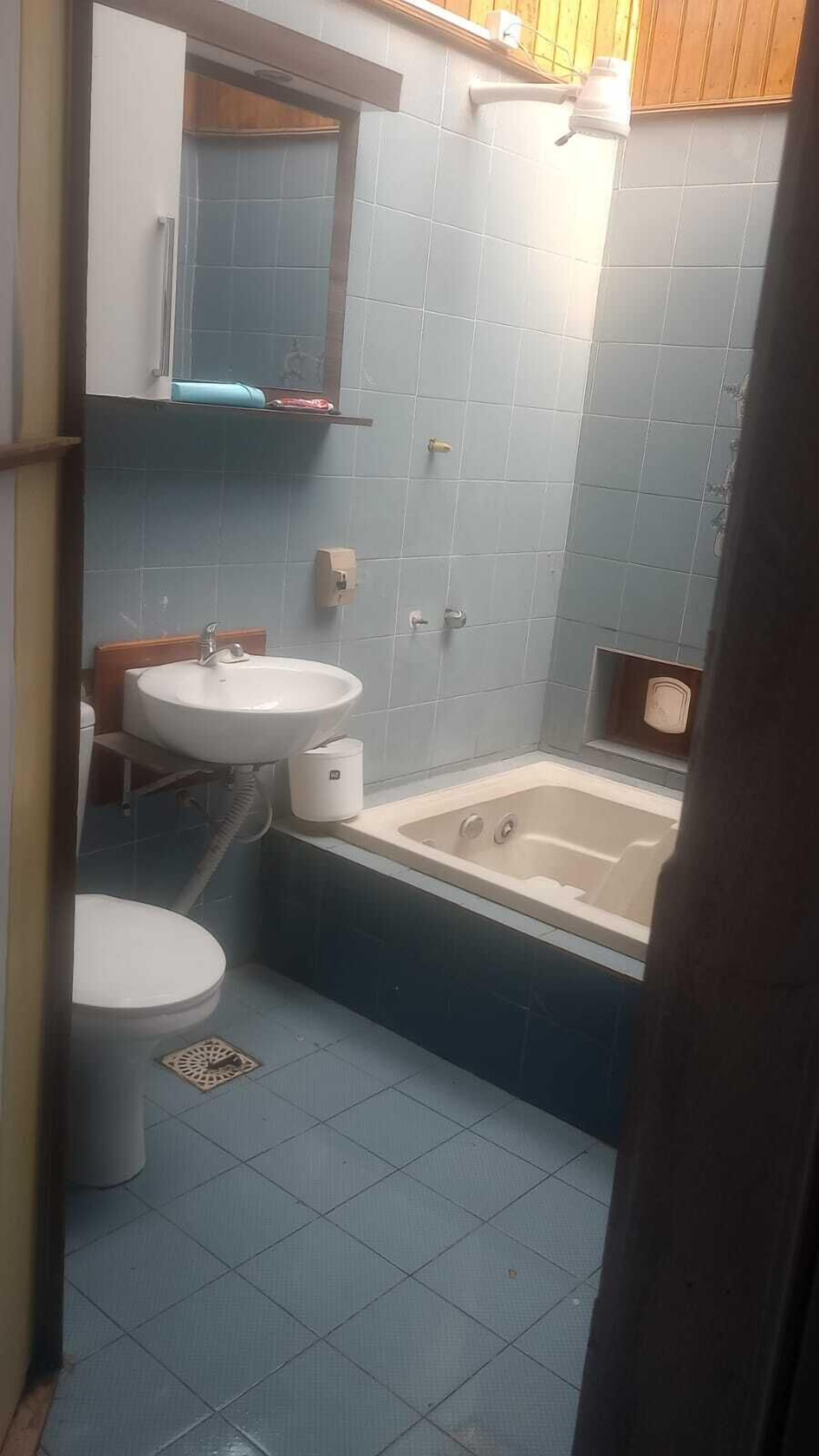 Un baño con bañera, dos lavamanos y un inodoro.