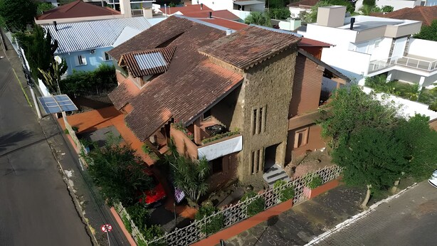 An aerial view of a building with a sloped roof, a visible balcony, and a small garden area. - Merlyn Pousadas (Lajeado)