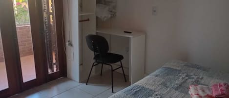 Un dormitorio con cama, una silla, un escritorio y un armario.