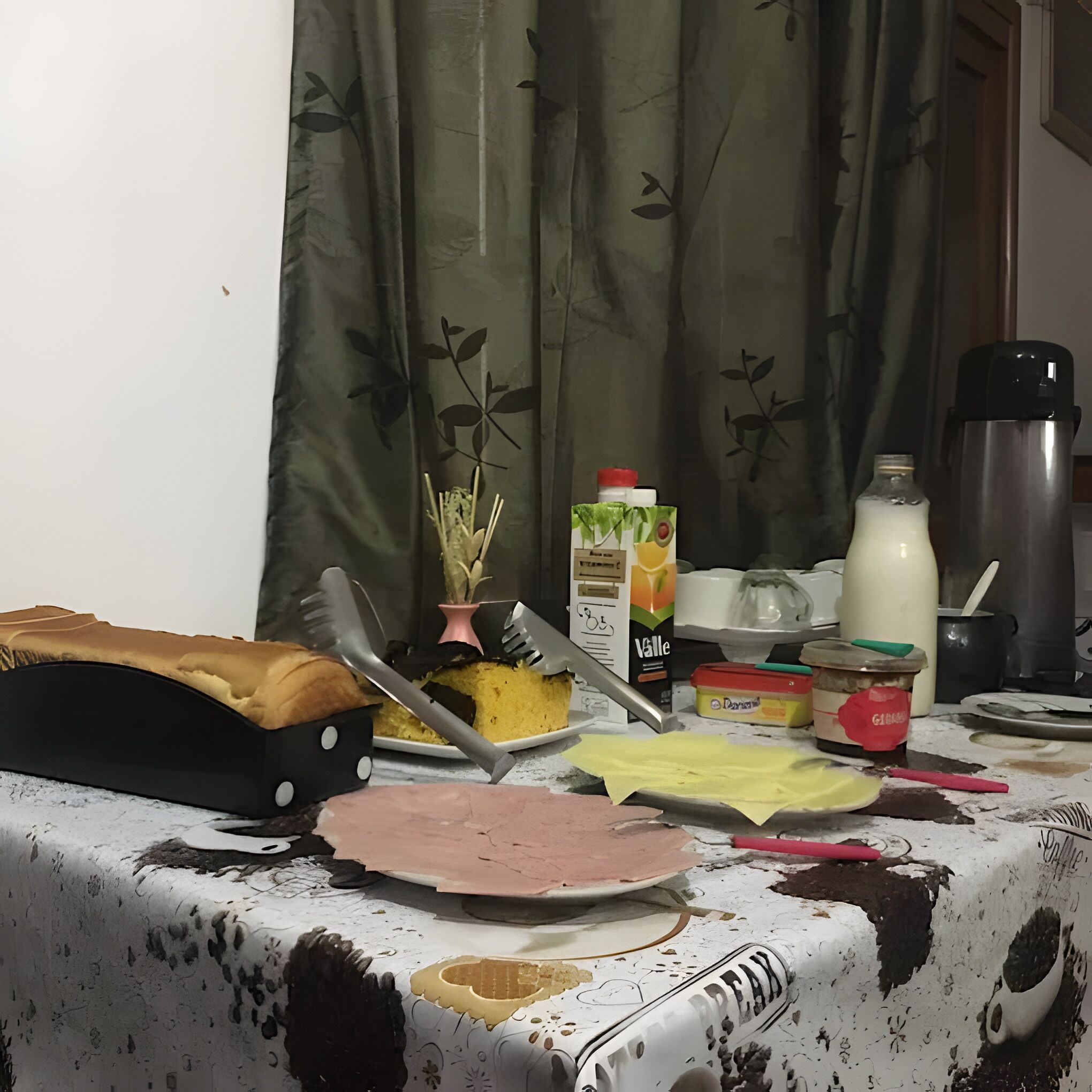 A kitchen counter with various items including a loaf of bread, a plate with a cake, a bottle of milk, a thermos, and a box of butter.