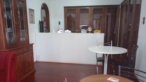 A dining area with a round table and chairs, a wooden cabinet, and a white counter with various items. - Merlyn Pousadas (Lajeado)