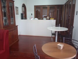 Uma sala de jantar com uma mesa redonda e cadeiras, um armário de madeira e um balcão branco com diversos objetos.