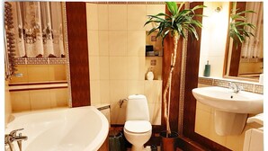 Un baño con bañera, inodoro, lavabo y una planta en maceta.