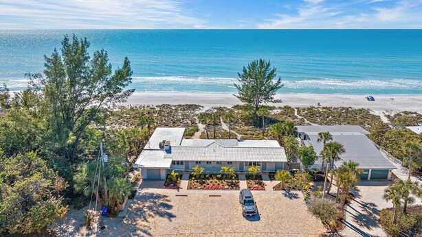 A beachfront property with a large house, a driveway, and a parking area. - Charming Beach Front Studio Steps to the Sand and Gulf (Longboat Key)