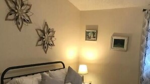 A bed with a laptop on it, a bedside lamp, and wall decorations.