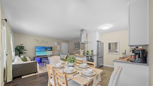 Una sala de estar moderna con comedor, cocina y televisor.