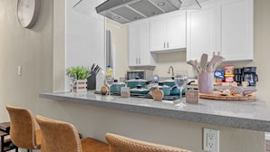Una cocina moderna con armarios blancos, encimera de granito y una zona de bar con taburetes.