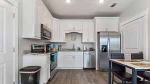 A modern kitchen with white cabinets, stainless steel appliances, and a dining area with a table and chairs.