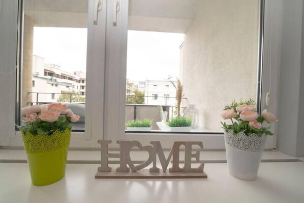 Enjoy a serene view of the surrounding area from this stylish space, featuring a large window and two potted plants.