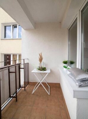Enjoy a peaceful retreat on this balcony with a table, window seat, and lush greenery.