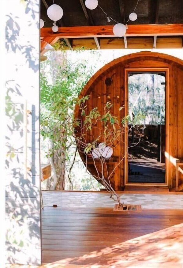 A wooden structure with a circular archway, a wooden deck, and a hanging plant.