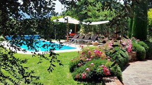 Ein Schwimmbecken mit Liegestühlen und ein Garten voller Blumen.