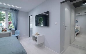 Relax in a spacious room with a large flat-screen TV, comfortable bed, and a bathroom with a sink and mirror.