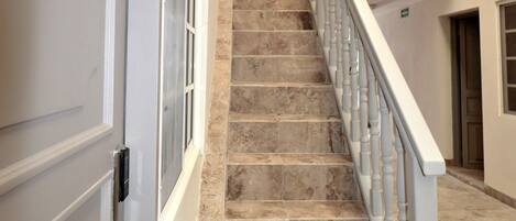 A staircase with marble steps leading to a landing with a railing. A door labeled "102" is visible on the left.