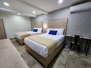 A hotel room with two beds, a desk, and a chair.