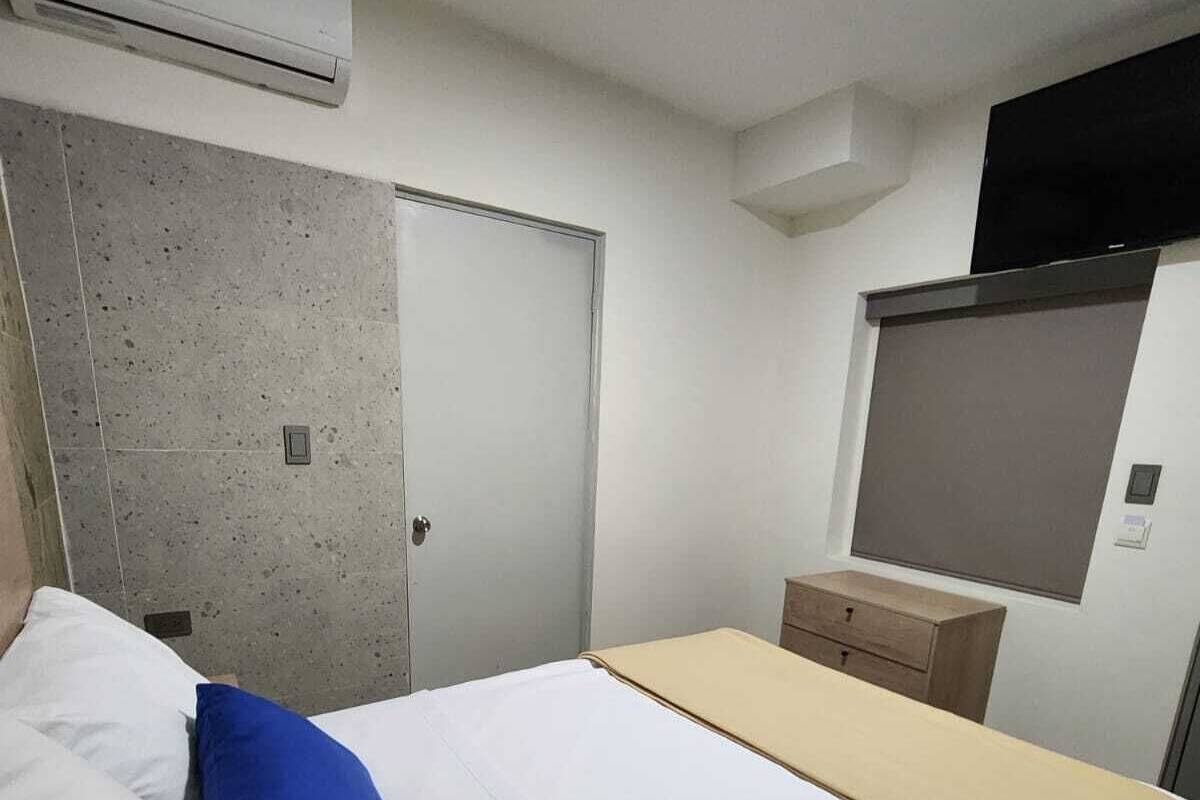 A bedroom with a bed, a wardrobe, a bedside table, and an air conditioning unit.